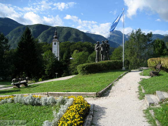 Park, spomenik in cerkev sv. Janeza Krstnika v ozadju