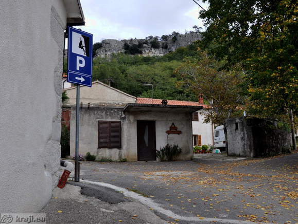 Direction sign for the parking area below the rock wall